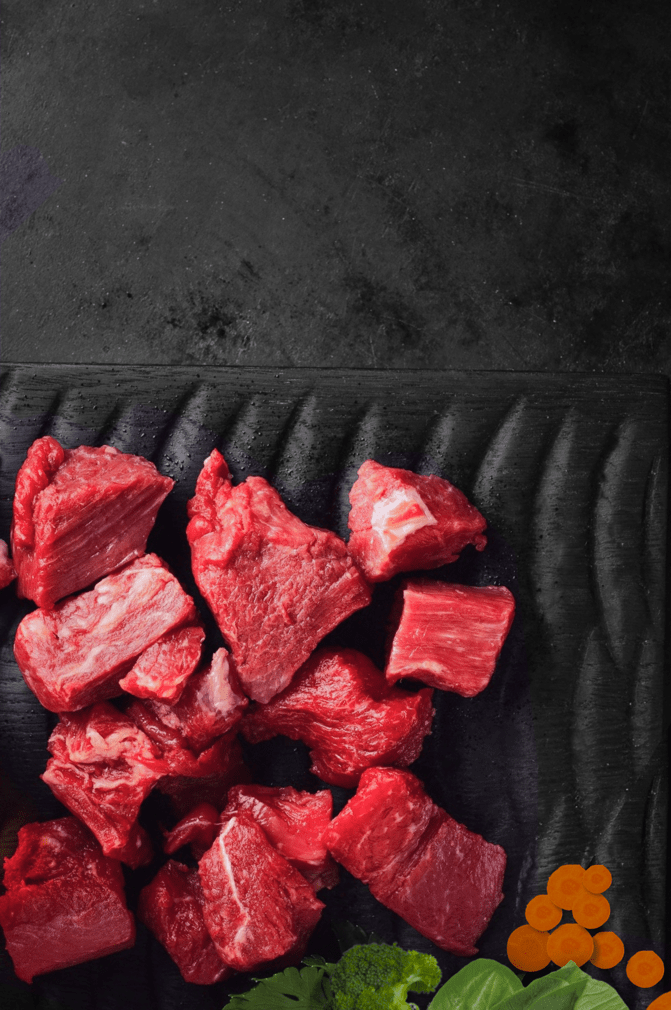Platter of chunks of raw meat and some vegetables